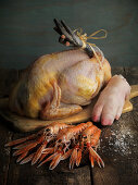 Still life with raw black chicken, pigs' foot, and Norway lobster