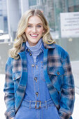 A young blonde woman wearing blue denim dungarees and a checked jacket