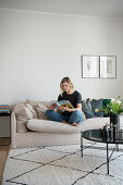 Blonde woman sitting on the sofa with magazine