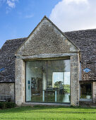 Exterior of converted barn with large window to kitchen-living room