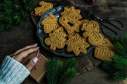 Woman hand and gingerbread cookies on wooden table