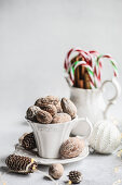 Vintage cup full of nuts, cinnamon sticks and candy canes on concrete background