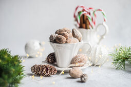 Vintage cup full of nuts, cinnamon sticks and candy canes on concrete background