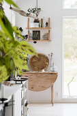 Folding wooden table, above it shelves on a white wall