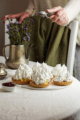 Frucht-Tartelettes mit Sahne und Baiserhaube, mit Puderzucker bestauben