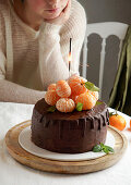 Schokoladen-Dripping-Cake mit Mandarinen und Wunderkerze