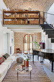 Piano in the living room with natural stone wall and bookshelf on gallery