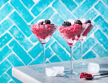 Mixed berry granita in a cocktail glass against a blue background