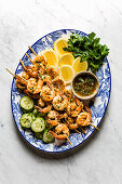 Grilled Shrimp skewers served on a blue ceramic plate with lemon and cucumber