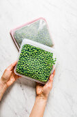 Putting blanched green peas in a storage tin