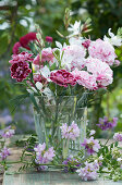 Small bouquet of carnation blossoms and magnificent candle, tendrils of crown vetch in front of it