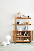 Wooden shelf with decorative objects, floor vase next to it