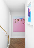 Colourful pictures in staircase with white walls