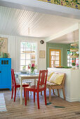 Red chairs at dining table in front of open kitchen in Swedish style