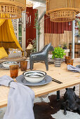 Set dining table with a horse figurine, above it bamboo hanging lamps