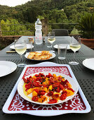 Gegrillte Pfirsiche mit sonnengetrockneten Tomaten auf gedecktem Tisch im Freien