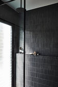 Shower area with black wall tiles