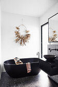 Black freestanding bathtub in front of white wall