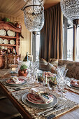 Festively set table below chandelier in cabin dining room