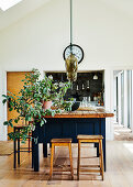 Blue kitchen island with reclaimed wood worktop, houseplant and pendant lamp