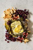 Feta baked in grape leaves served with baked grapes, pita chips, and figs
