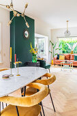 View across oval dining table into living area with dark green wall