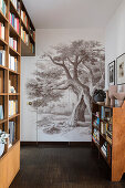 Floor-to-ceiling bookshelf and wallpaper with tree motif in the hallway