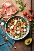 Salad made of rocket, cherry tomatoes, avocado, mini mozzarella and prosciutto