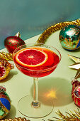 Blutorangen-Drink im Cocktailglas und Weihnachtsdekoratiion