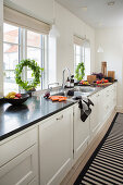 White kitchen counter with black granite worktop in front of windows