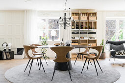 Round table and designer chairs in dining area with wine rack in background