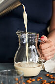 Pouring homemade almond milk into a jug