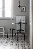 Slender black table and stools on tiled floor