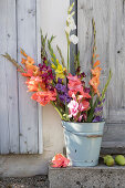 Bouquet of gladioli in enamelled bucket, pears