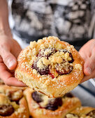 Man holding yeast roll with plums and crumble