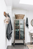 Metal cupboard in rustic bathroom with grey towels