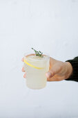 A hand holding a glass of homemade lemonade
