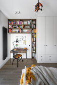 Small writing corner with bookshelves next to floor-to-ceiling wardrobe in teenager's bedroom
