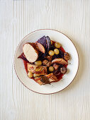 Pork fillet wrapped in bacon with grapes, chestnuts, and red cabbage