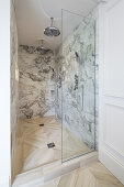 Duschbereich mit Marmorwänden und Glastür