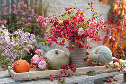 Rose-pink autumn bouquet of roses, rose hips and twigs of peony, grey pumpkins for eating