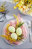 An Easter table with coloured eggs in a muslin nest