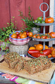 Etagere mit verschiedenen Tomaten und Tomaten-Kastenbrot mit Kürbiskernen
