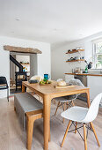 White kitchen with dining table and bench in light wood and classic chairs