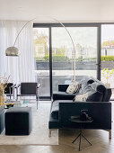 Black sofa and arc lamp in front of terrace doors in living room