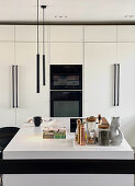 White fitted kitchen with black appliances and island counter