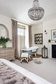 Freestanding bathtub with privacy screen in front of window in a light bedroom