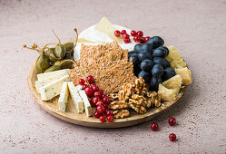 A cheese platter with crispbread, capers, redcurrants, grapes and nuts