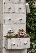 Alter Apothekerschrank mit Vintage Utensilien im Garten