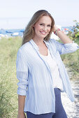 Langhaarige Frau in frühlingshaftem blau-weißem Outfit am Strand